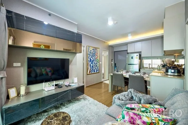 Condominium for rent in Phra Khanong, Bangkok - Media wall with large TV and storage opposite the sofa, open to the dining and kitchen area.