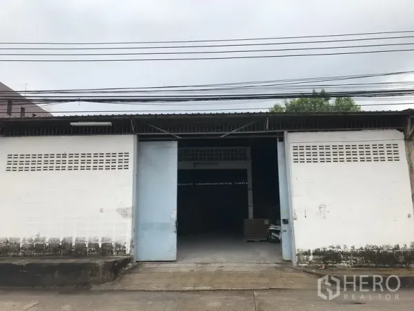 คลังสินค้า ให้เช่าในMueang Samut Prakan, Samut Prakan - ด้านหน้าโกดังชั้นเดียว ประตูบานเลื่อนโลหะกว้าง พื้นคอนกรีตและจุดขนถ่ายสินค้า