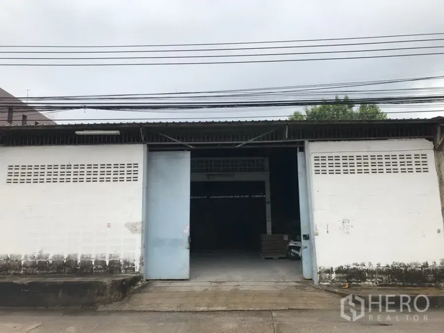 คลังสินค้า ให้เช่าในMueang Samut Prakan, Samut Prakan - ด้านหน้าโกดังชั้นเดียว ประตูบานเลื่อนโลหะกว้าง พื้นคอนกรีตและจุดขนถ่ายสินค้า