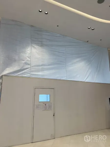 零售空间 出租 - 现代商场走道内，临时围挡与单门封闭的在建商铺。