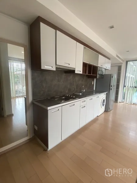 คอนโด ให้เช่าในPathum Wan, Bangkok - ครัวแบบแถวยาว ตู้สีขาว เตาไฟฟ้า ตู้เย็น และเครื่องซักผ้า ข้างหน้าต่างบานใหญ่