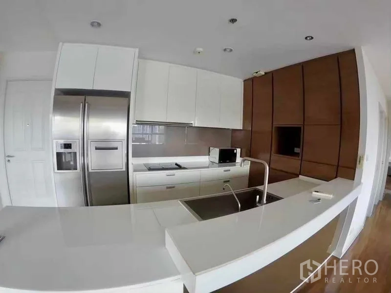Condominium for rent or sale in Khlong San, Bangkok - Close view of minimalist white kitchen with built-in hob and double-door fridge.