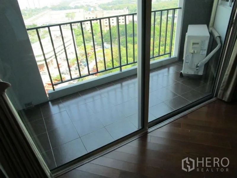 Condominium for sale in Huai Khwang, Bangkok - Private balcony with sliding glass doors, tiled floor, railing, and city view