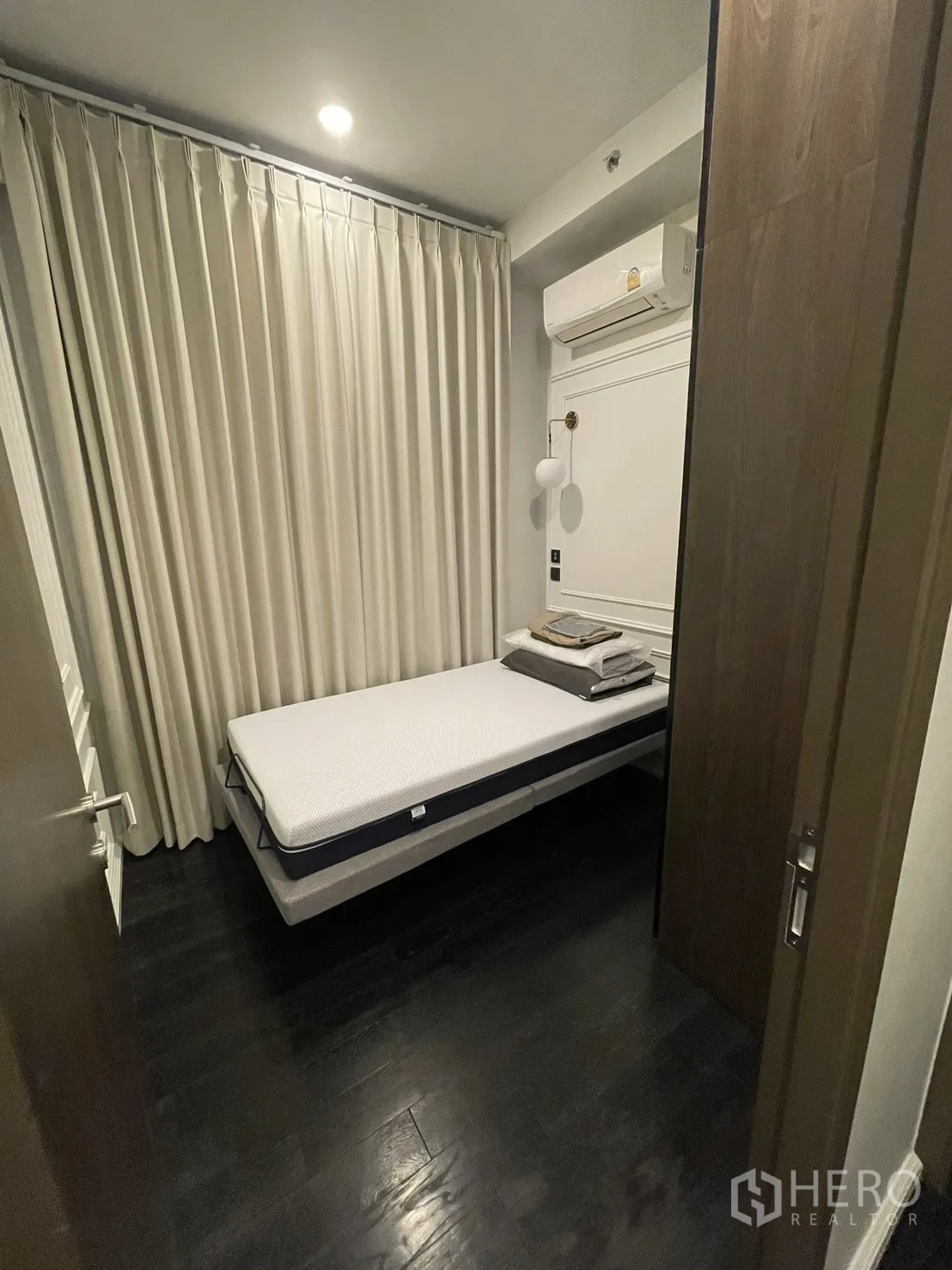 Condominium for rent in Watthana, Bangkok - Second bedroom with full curtains, single bed, and wall sconce.