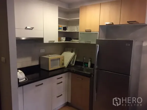 คอนโด ให้เช่าในPhaya Thai, Bangkok - ครัวรูปตัวแอลพร้อมตู้ลอยและตู้ล่าง โทนขาวไม้ เคาน์เตอร์สีดำ ไมโครเวฟ และตู้เย็นสแตนเลส