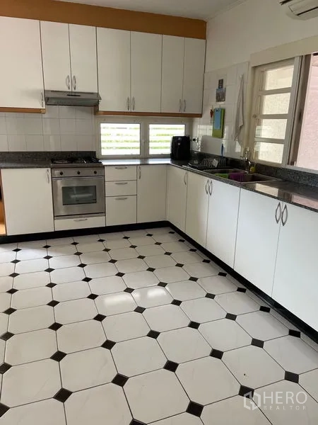 Detached House for rent in Bang Phli, Samut Prakan - L-shaped kitchen with white cabinetry, granite countertops, and a stainless oven.