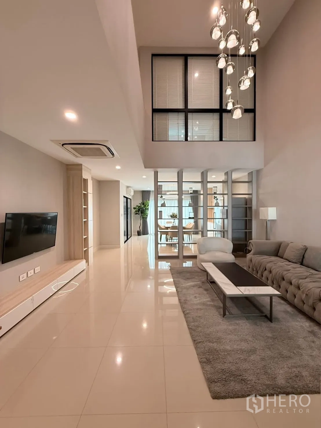 Townhouse for rent in Saphan Sung, Bangkok - Double-height living room with chandelier, sofa set and TV wall.