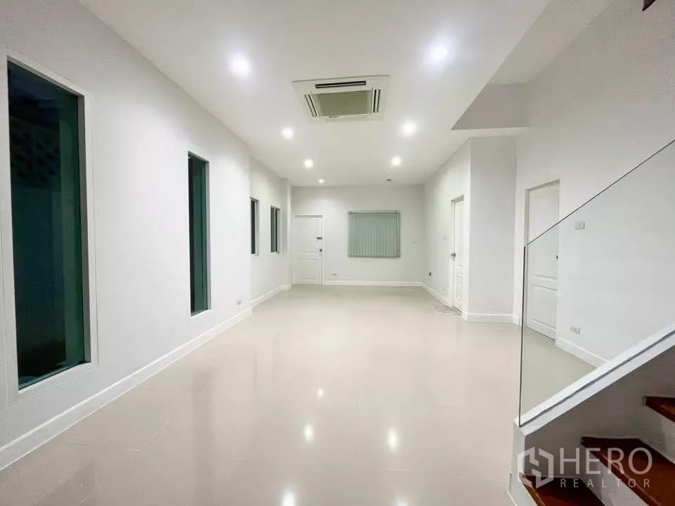Home Office for rent in Bueng Kum, Bangkok - Large white hall with recessed lighting and a glass balustrade by the stairs.