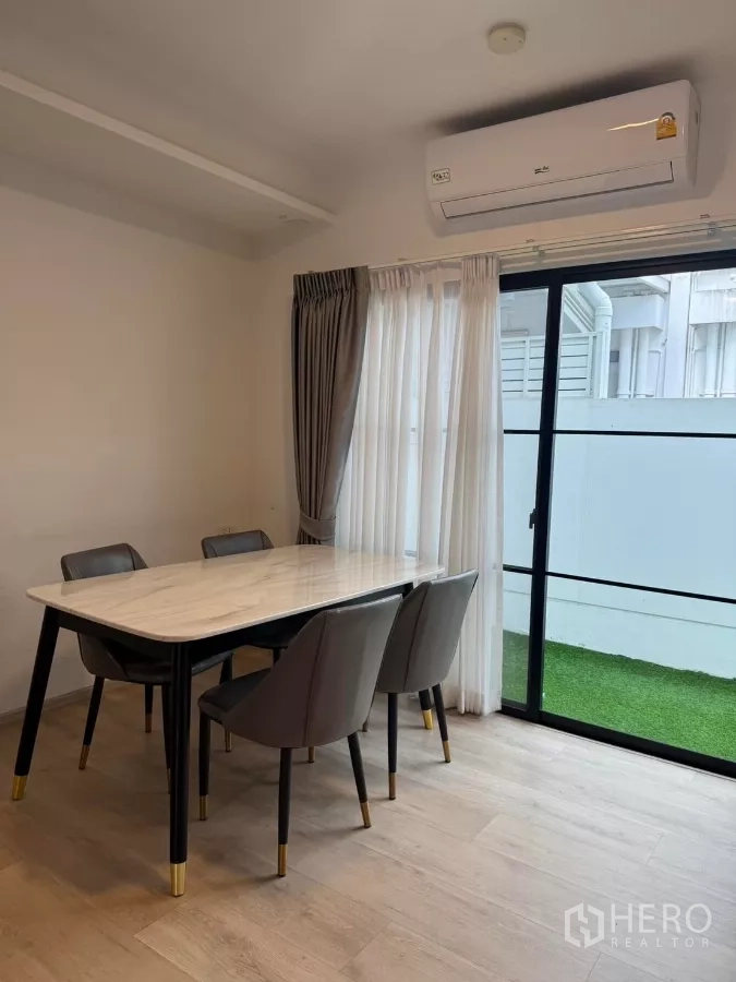 Townhouse for rent in Bang Phli, Samut Prakan - Dining space with air conditioner and sliding glass door to a small grassed yard.