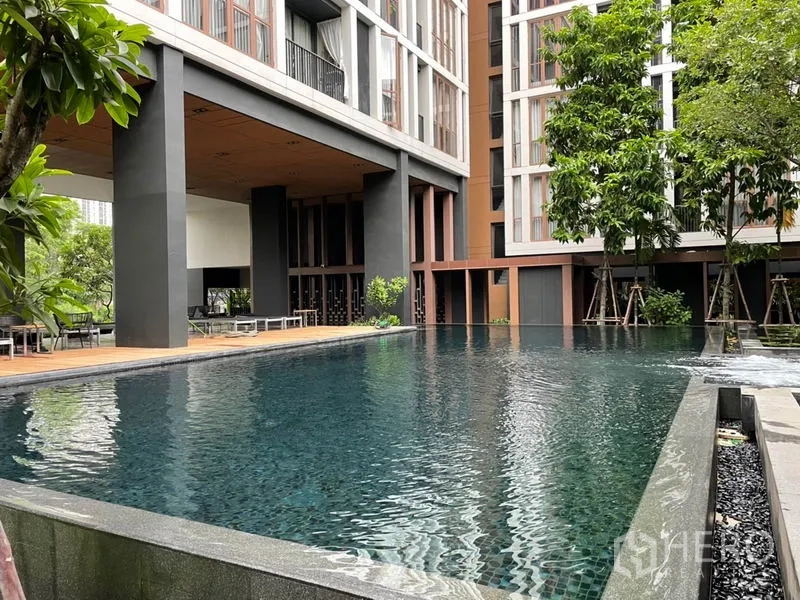 Condominium for sale in Watthana, Bangkok - Resort-style swimming pool surrounded by trees and a timber deck.