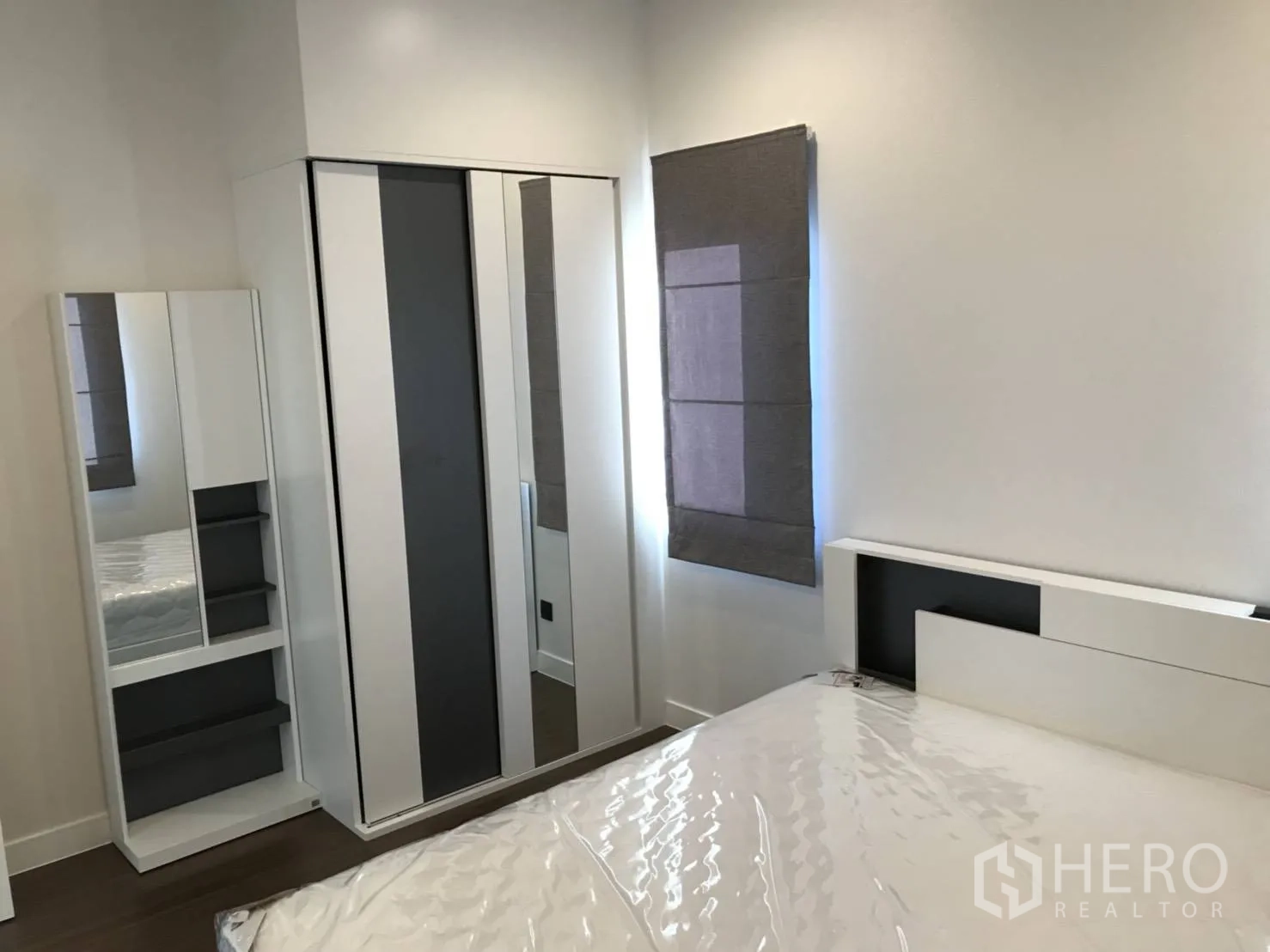 Detached House for rent in Bang Kapi, Bangkok - Guest bedroom featuring white wardrobe with mirrors and bed frame by a window.