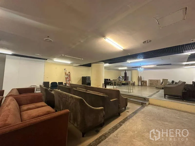 零售空间 出租 - 开放式零售展厅，带沙发、抬高平台、立柱与天花照明