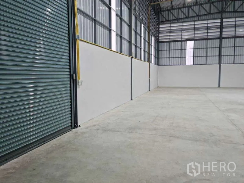 货栈 出租在Bang Bua Thong, Nonthaburi - 靠墙通道视角，高窗与通风百叶，混凝土地面平整。