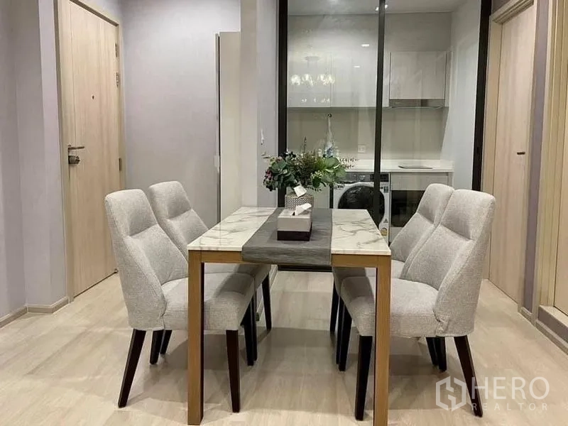 Condominium for rent in Pathum Wan, Bangkok - Dining area for four beside glass-partitioned kitchen in soft neutral tones.