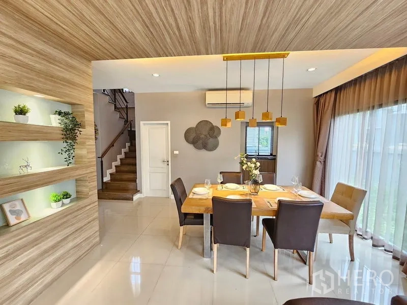 Detached House for rent in Prawet, Bangkok - Dining area with six-seat wooden table, pendant lighting, and display niches.