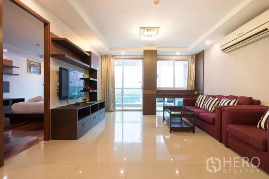 คอนโด ให้เช่าในWatthana, Bangkok - โถงนั่งเล่นโซฟาสีแดง ชุดชั้นวางทีวี และประตูสู่ระเบียง