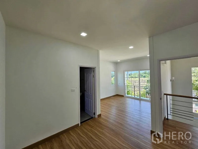 Detached House for rent in Thanyaburi, Pathum Thani - Upstairs living area with laminate floors and sliding doors to a balcony