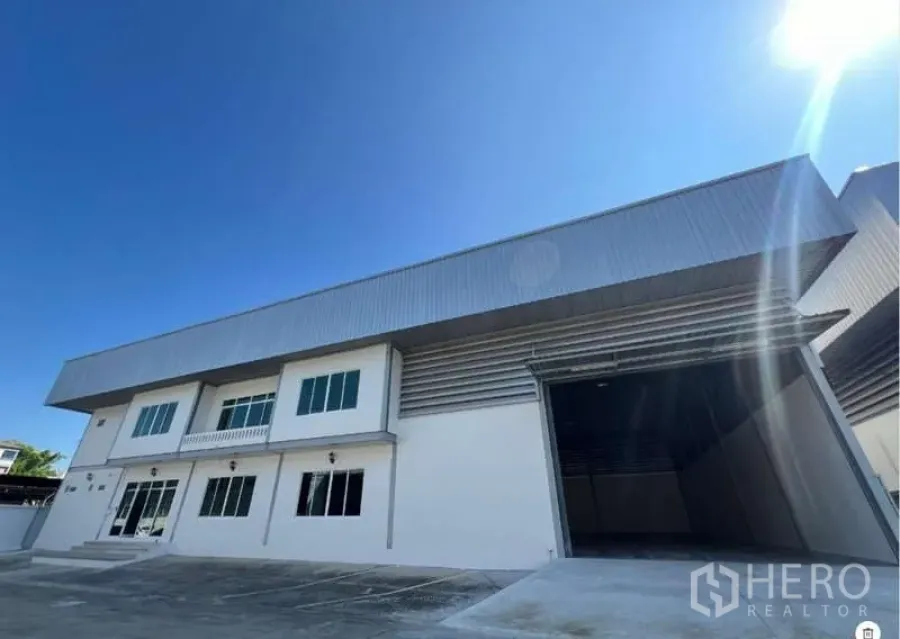 货栈 出租在Prawet, Bangkok - 仓库正立面，装卸口与车道，阳光明媚。