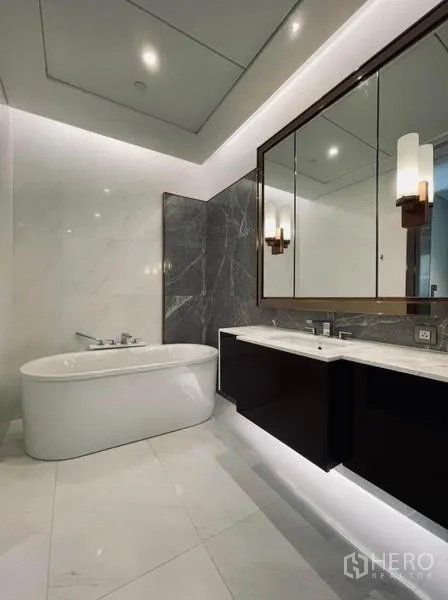 Condominium for rent in Pathum Wan, Bangkok - Luxury bathroom with freestanding bathtub, marble walls, and double-sink vanity.