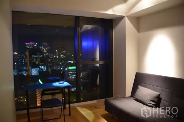 公寓 出租或出售在Sathon, Bangkok - 多功能房配沙发床与书桌，窗外夜景尽收眼底。