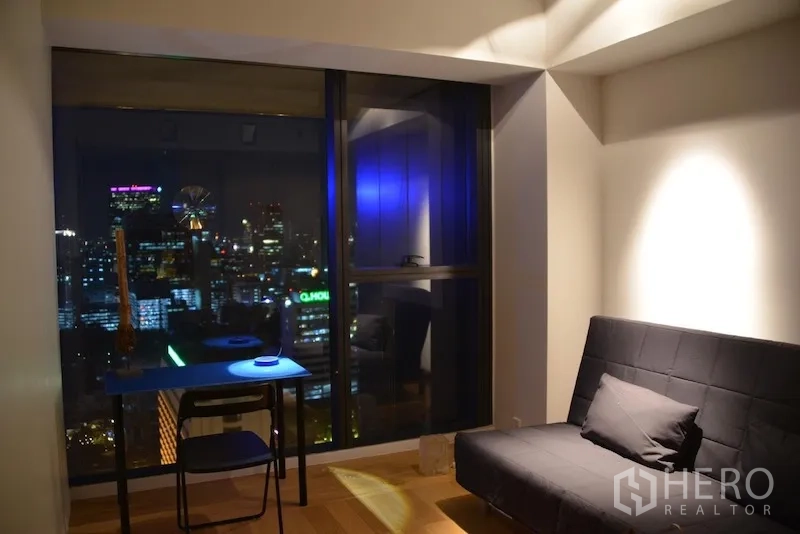 公寓 出租或出售在Sathon, Bangkok - 多功能房配沙发床与书桌，窗外夜景尽收眼底。