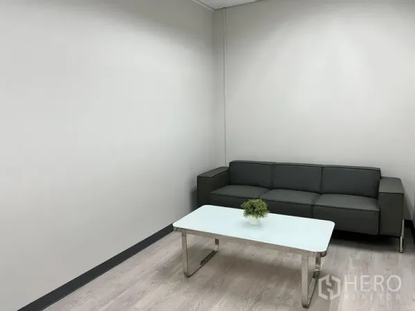 Office Space for rent in Sathon, Bangkok - Sathon office lounge with gray sofa and white coffee table on light wood floors.