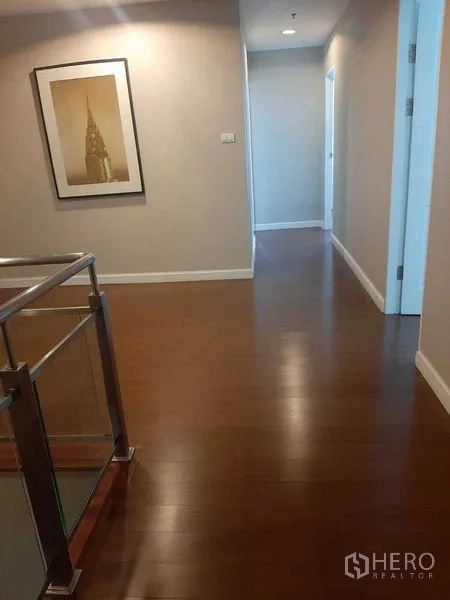 Condominium for rent or sale in Huai Khwang, Bangkok - Wide upstairs hallway with wooden floor, artwork, and access to bedrooms.