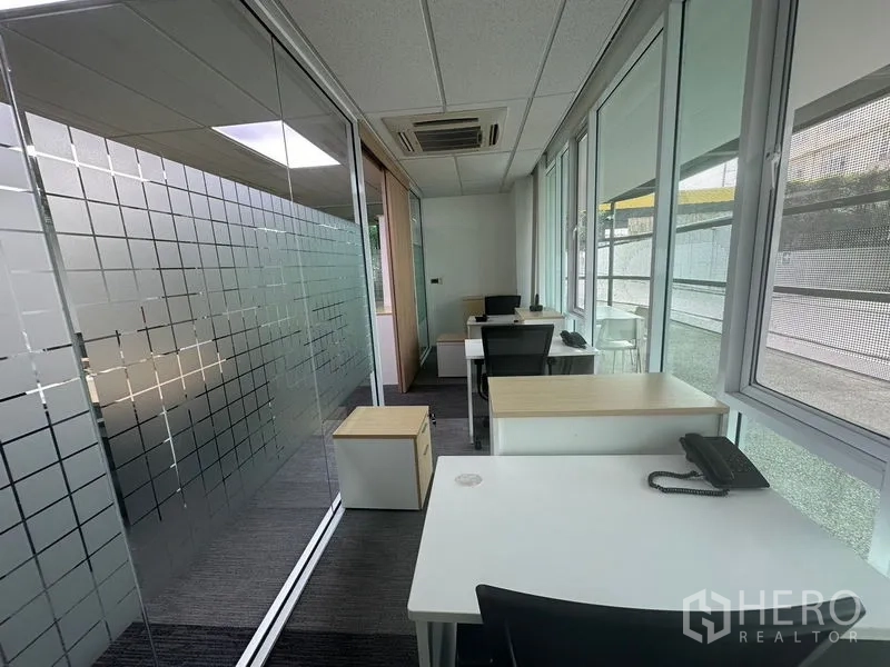 Office Space for rent - Glass-lined corridor office with multiple desks, telephones, and natural light.