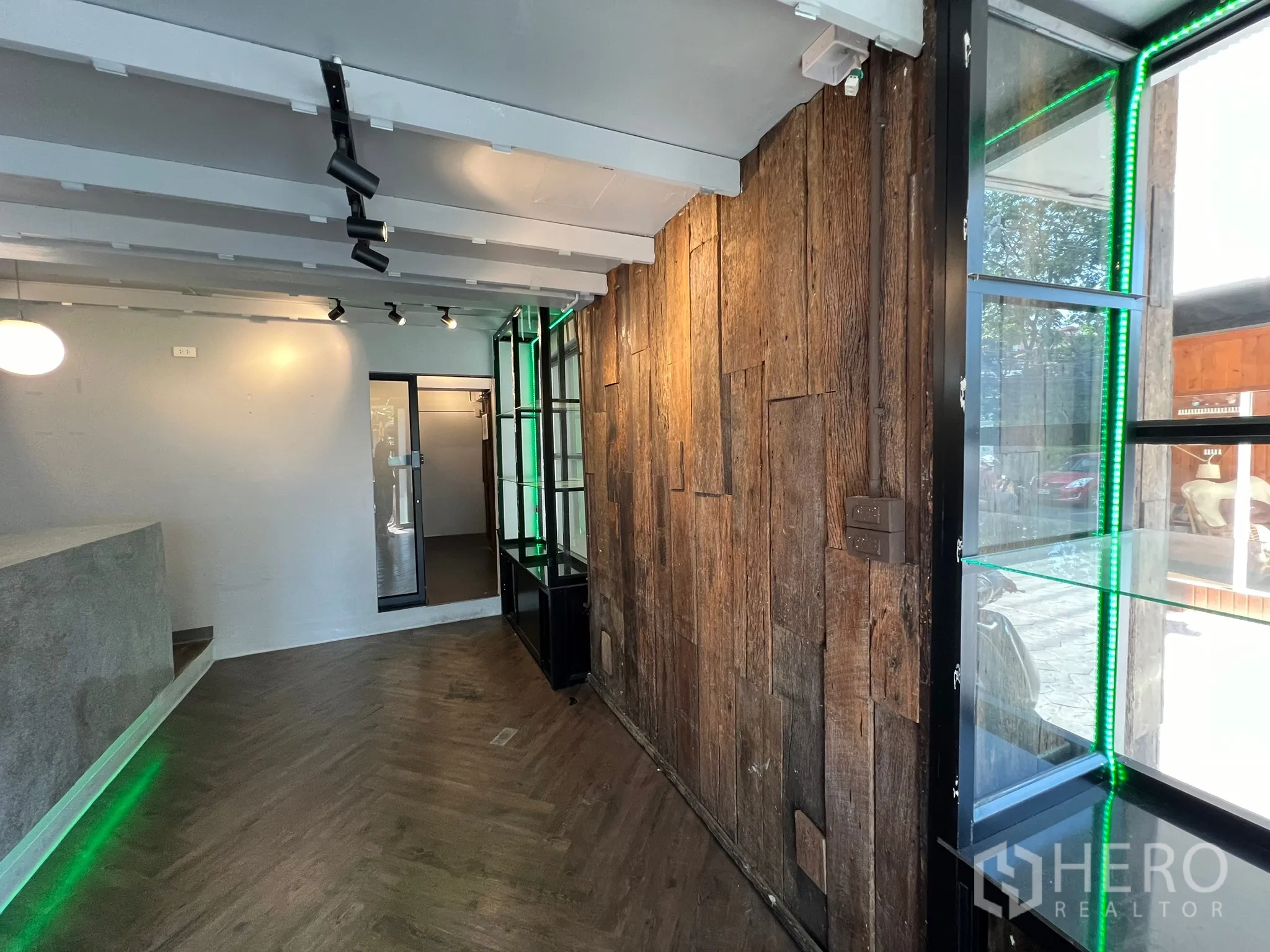 零售空间 出租在Watthana, Bangkok - 近景走道，原木特色墙、玻璃展示柜与轨道灯