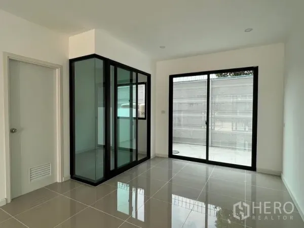 Townhouse for rent in Bang Kapi, Bangkok - Glass-enclosed multipurpose nook beside a sliding door in a minimalist living space.
