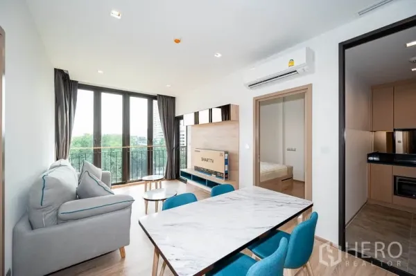 Condominium for rent in Watthana, Bangkok - Open living room connecting dining area, balcony and kitchen entrance.