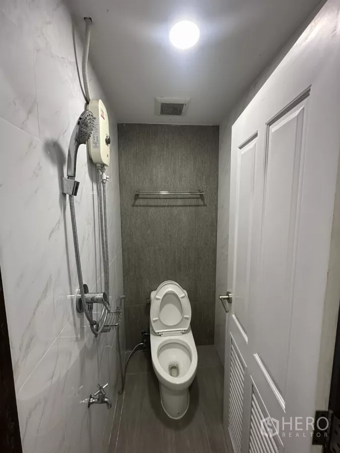 零售空间 出租在Watthana, Bangkok - 紧凑型卫生间，坐便与手持花洒，灰色瓷砖墙面