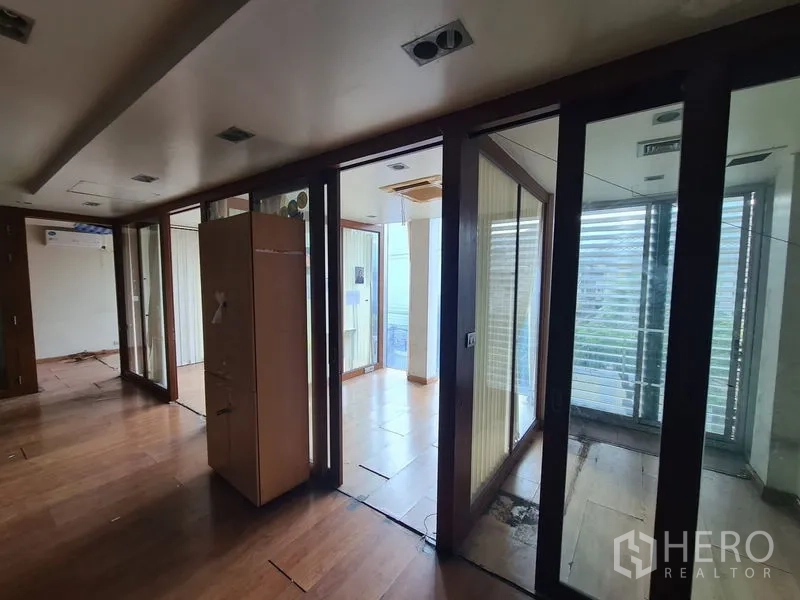 办公空间 出租在Bang Rak, Bangkok - 玻璃房间连成的走廊，通向带遮阳百叶的阳台。