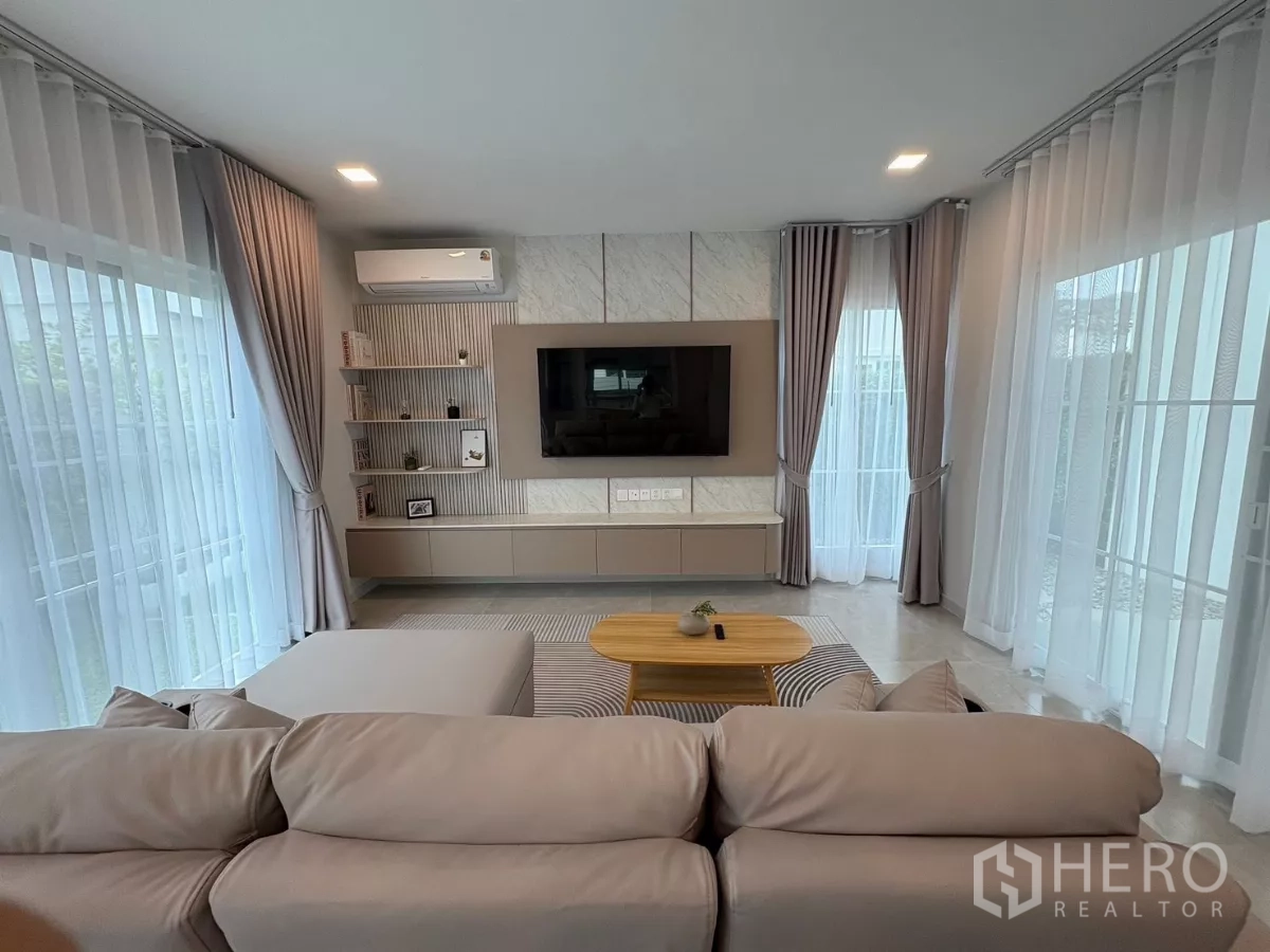 Detached House for rent or sale in Bang Phli, Samut Prakan - Cozy lounge with L-shaped sofa, coffee table and wraparound windows.