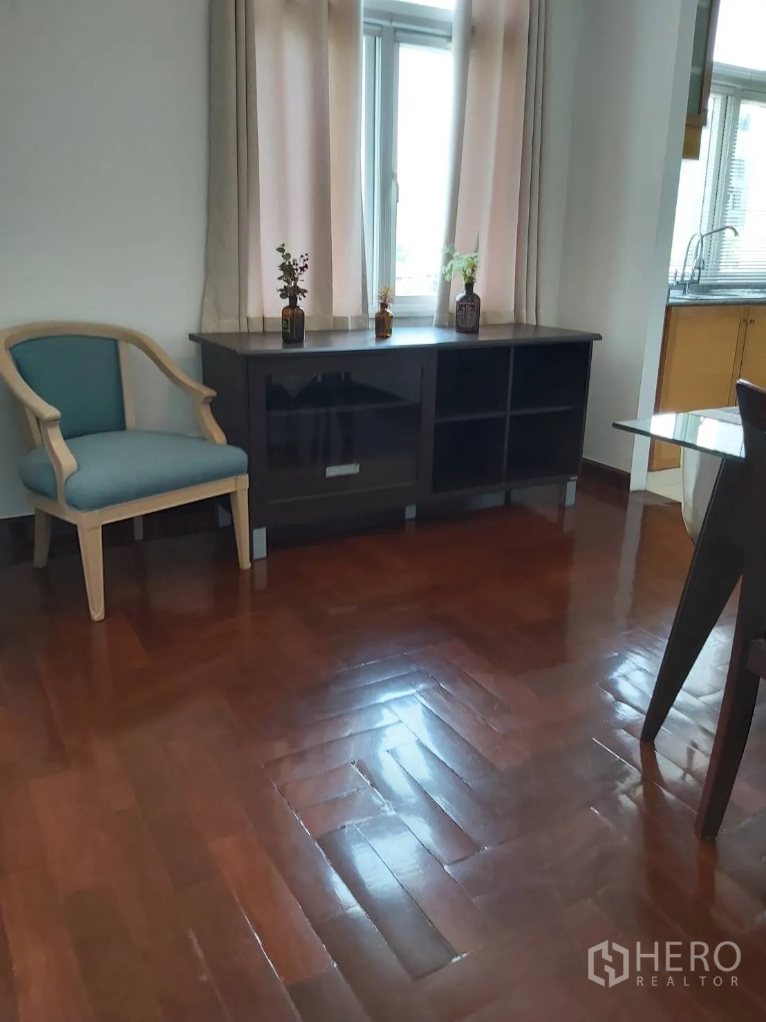 Apartment for rent in Khlong Toei, Bangkok - Living area corner with console cabinet, accent chair, and glossy parquet flooring.