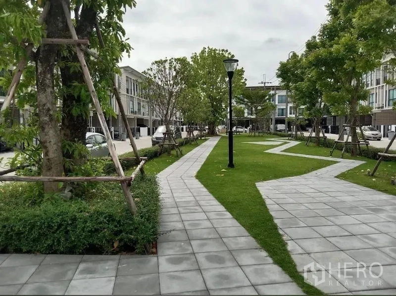 Townhouse for rent in Bang Kapi, Bangkok - Landscaped community park with walking paths, trees, and street lamps between townhouse rows.
