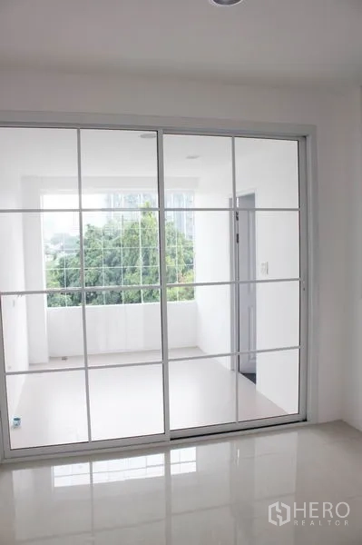 Home Office for rent in Khlong Toei, Bangkok - Sliding glass doors opening to a light-filled balcony with treetop views.