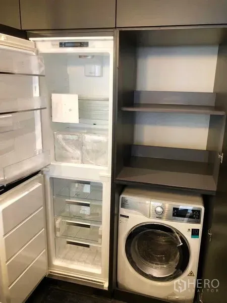 Condominium for rent - Utility cabinet with open refrigerator, storage shelves and a front-load washer dryer.