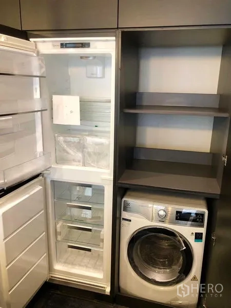 Condominium for rent - Utility cabinet with open refrigerator, storage shelves and a front-load washer dryer.