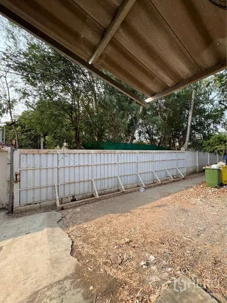货栈 出售在Bang Bua Thong, Nonthaburi - 服务庭院与金属推拉门，围栏与树木环绕。