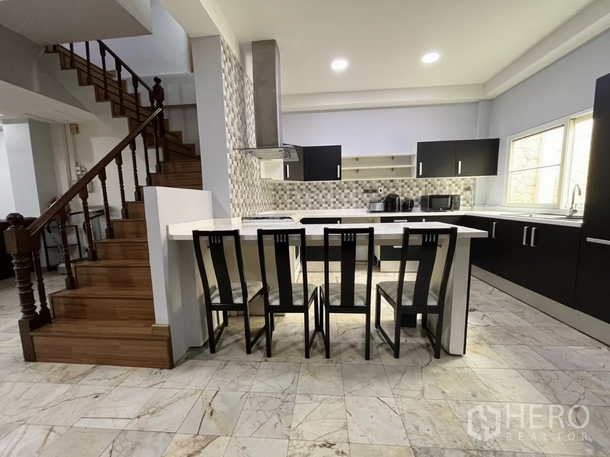 Home Office for rent - Open‑plan kitchen with island breakfast bar beside a wooden staircase