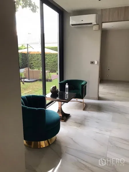 บ้าน ให้เช่าในWatthana, Bangkok - มุมนั่งเล่นสบาย เก้าอี้กำมะหยี่สีเขียวสองตัว กับโต๊ะข้าง ข้างหน้าต่างสูงมองเห็นสวนส่วนตัว