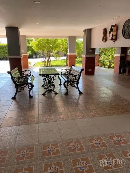 Detached House for sale in Bang Bo, Samut Prakan - Covered patio with tiled floor and wrought-iron benches facing the garden.