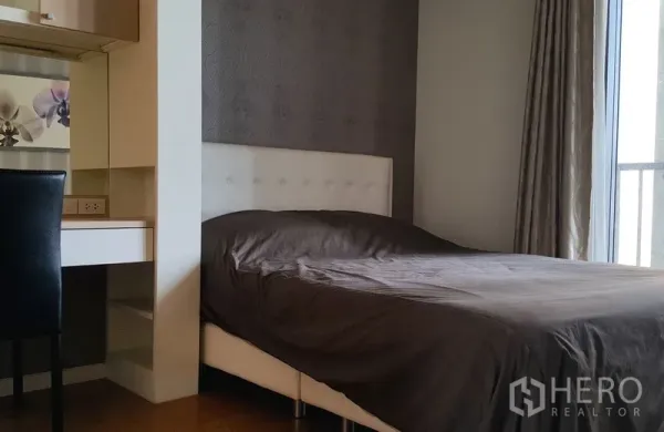 Condominium for rent in Sathon, Bangkok - Third bedroom featuring a dark accent wall, study desk with floral backsplash, and a window to a balcony.