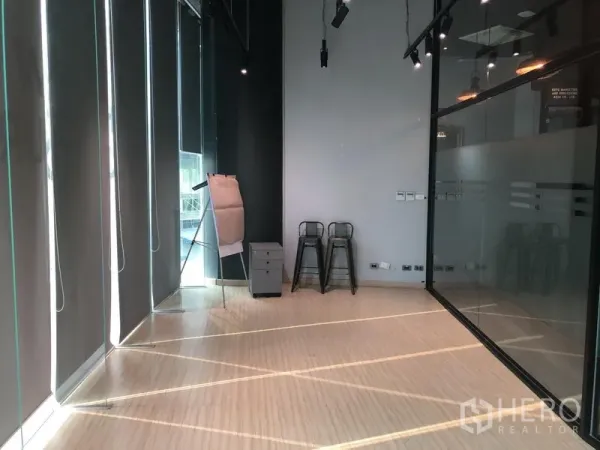 สำนักงาน ให้เช่าในKhlong Toei, Bangkok - มุมออฟฟิศพร้อมม่านกรองแสง ผนังกระจก เก้าอี้สตูล และพื้นไม้ เหมาะสำหรับประชุมขนาดเล็กหรือจัดวางเวิร์กสเตชัน