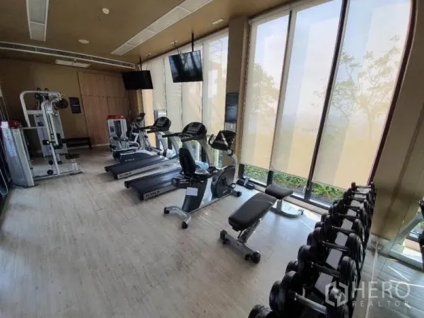 Condominium for sale in Ratchathewi, Bangkok - Condominium fitness center with treadmills, bikes, weight machines and floor-to-ceiling windows.