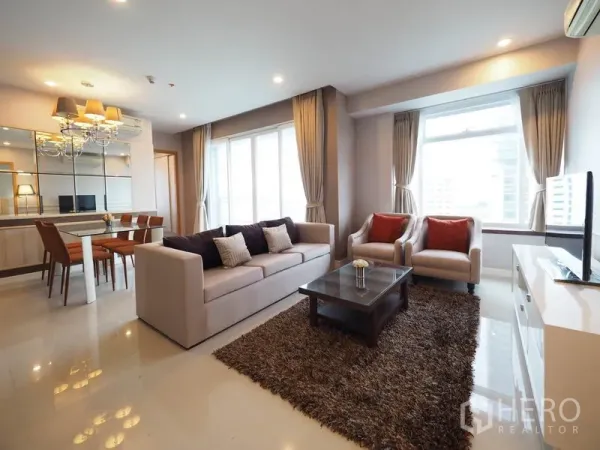 Condominium for rent in Ratchathewi, Bangkok - Open-plan living and dining room with sofa set, coffee table, rug and mirrored wall filled with natural light.