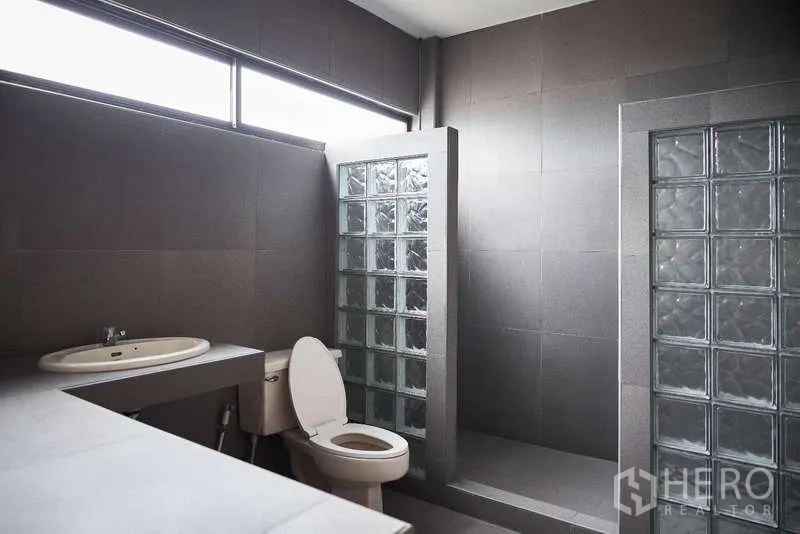 ทาวน์เฮาส์ ให้เช่าในKhlong Toei, Bangkok - ห้องน้ำโทนเทาพร้อมฉากกั้นบล็อกแก้วและช่องแสงยาว