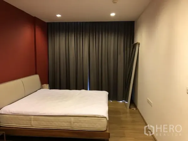 Condominium for rent in Watthana, Bangkok - Primary bedroom with red accent wall, king bed and full-length blackout curtains.