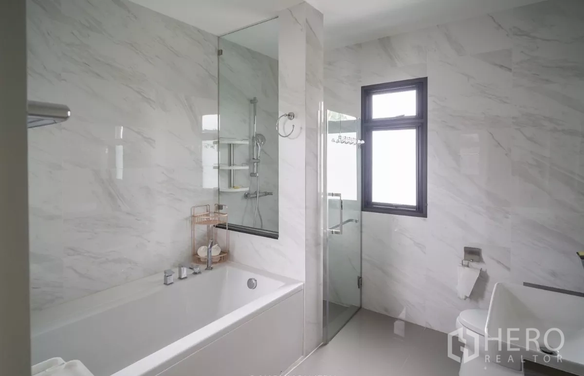 Detached House for rent or sale in Saphan Sung, Bangkok - Bathroom with bathtub and separate glass shower, finished in marble tiles.